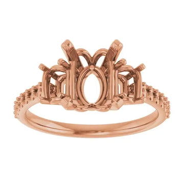 Rose gold engagement ring setting with oval stone center, decorative split shoulders, and textured band.