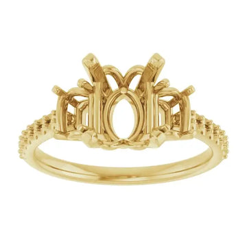 Gold engagement ring setting with oval stone center, decorative side details, and textured band.