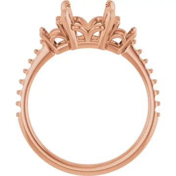 Rose gold engagement ring setting with ornate crown-style head and studded band, designed for emerald stone placement.