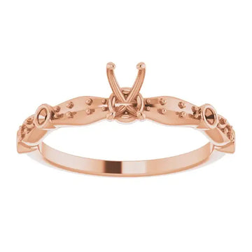 Rose gold engagement ring setting with ornamental prongs and studded band for emerald stone.