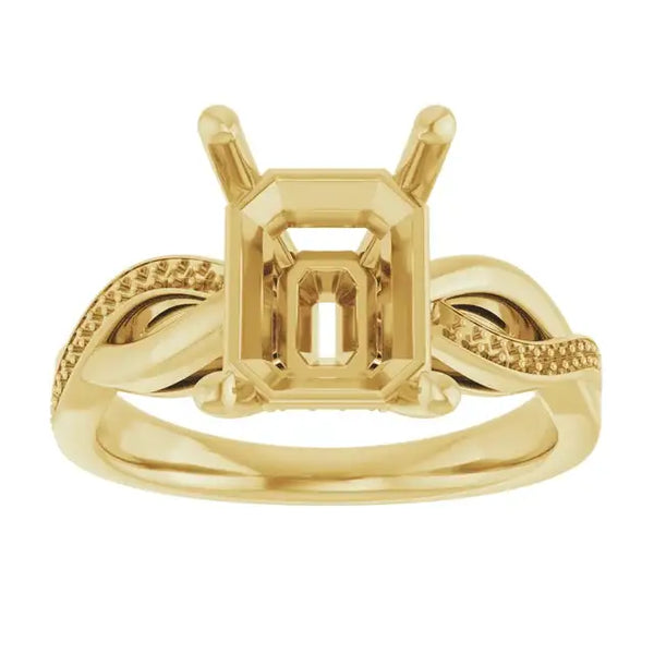 Gold engagement ring setting with emerald-cut stone holder and textured twisted band design.