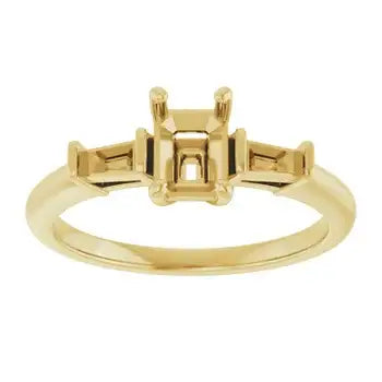 Gold engagement ring setting with empty emerald-cut center stone mount and two smaller side stone settings.
