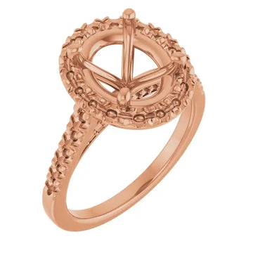 Rose gold engagement ring setting with oval stone mount and beaded halo accents on band.