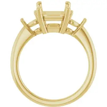 Gold-toned engagement ring setting with empty emerald-cut stone prongs, shown from side angle.