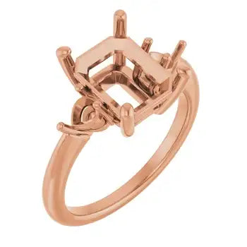 Rose gold engagement ring setting with four-prong emerald-cut stone holder and decorative band.