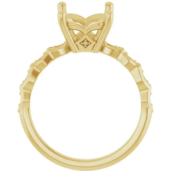 Gold engagement ring setting with French-set diamonds along the band and decorative four-prong head for emerald stone.