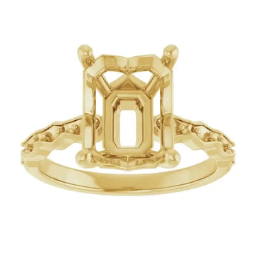 Gold engagement ring setting with emerald-cut stone holder and decorative shoulder details, shown from front view.