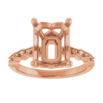 Rose gold French-set engagement ring setting with emerald-cut center stone housing and decorative side details.