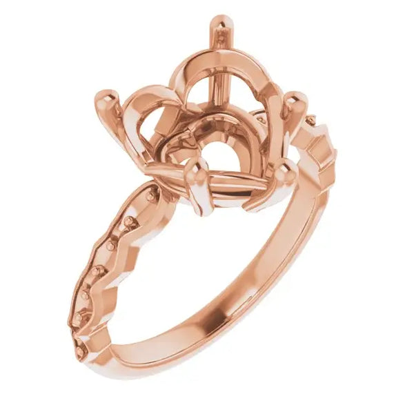 Rose gold engagement ring setting with ornate crown-style head and decorative band for heart-shaped stone.