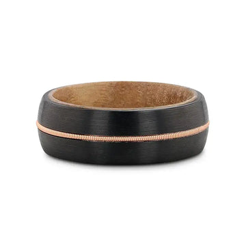 Flat lay of the 8mm black tungsten ring showing the whiskey barrel wood inner sleeve and brass guitar string inlay