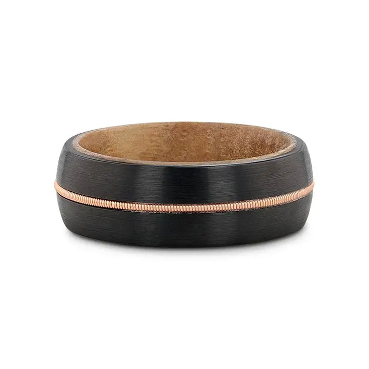 Flat lay of the 8mm black tungsten ring showing the whiskey barrel wood inner sleeve and brass guitar string inlay