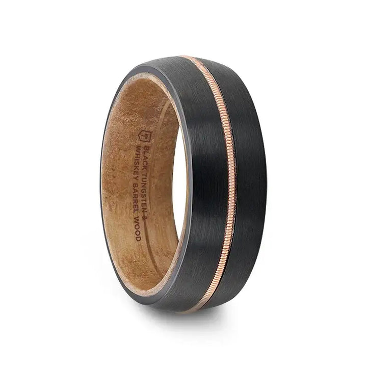 Angled view of an 8mm black tungsten ring with a central brass guitar string inlay and whiskey barrel wood inner sleeve