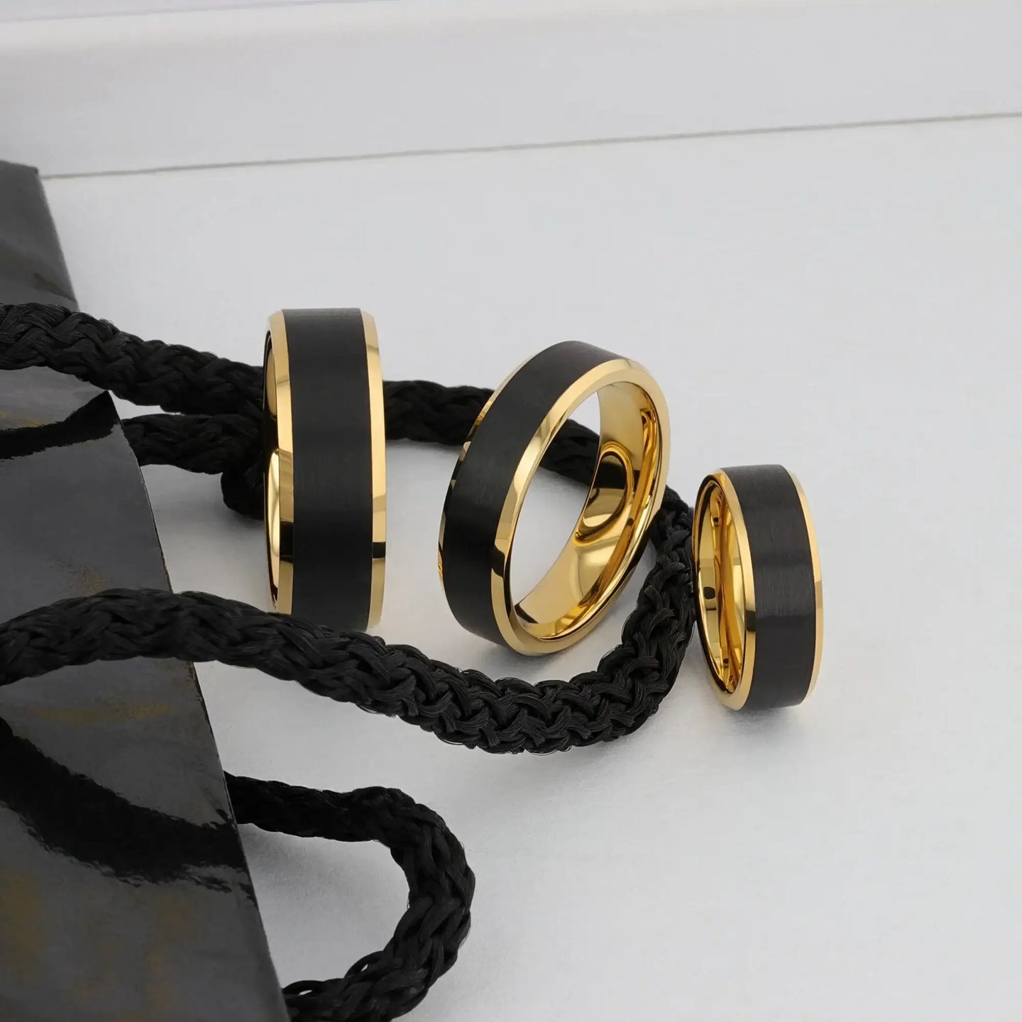 Ring worn on a hand to show scale, with black brushed center and polished gold beveled edges