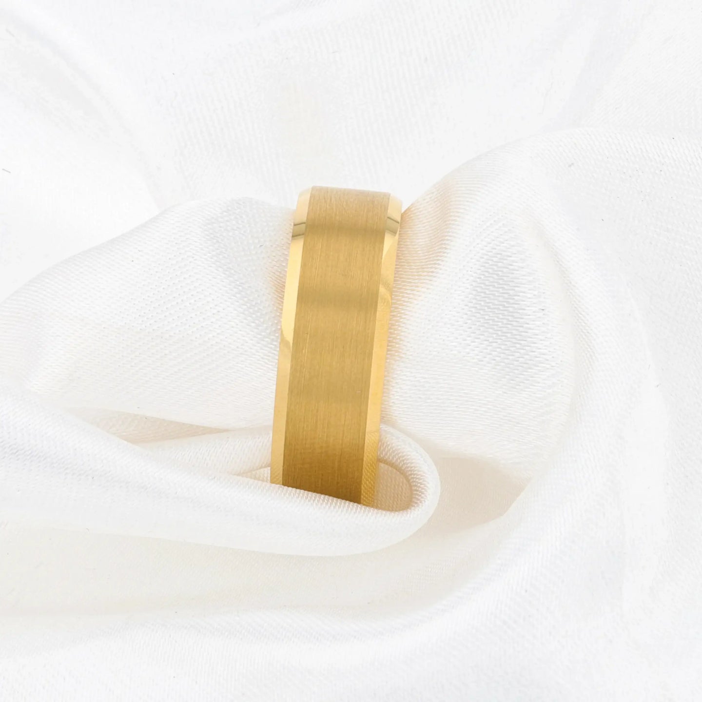 Gold-plated tungsten ring displayed on white fabric, showing brushed center strip.