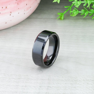 Studio shot of the INFINITY black tungsten ring with beveled edges on a reflective surface