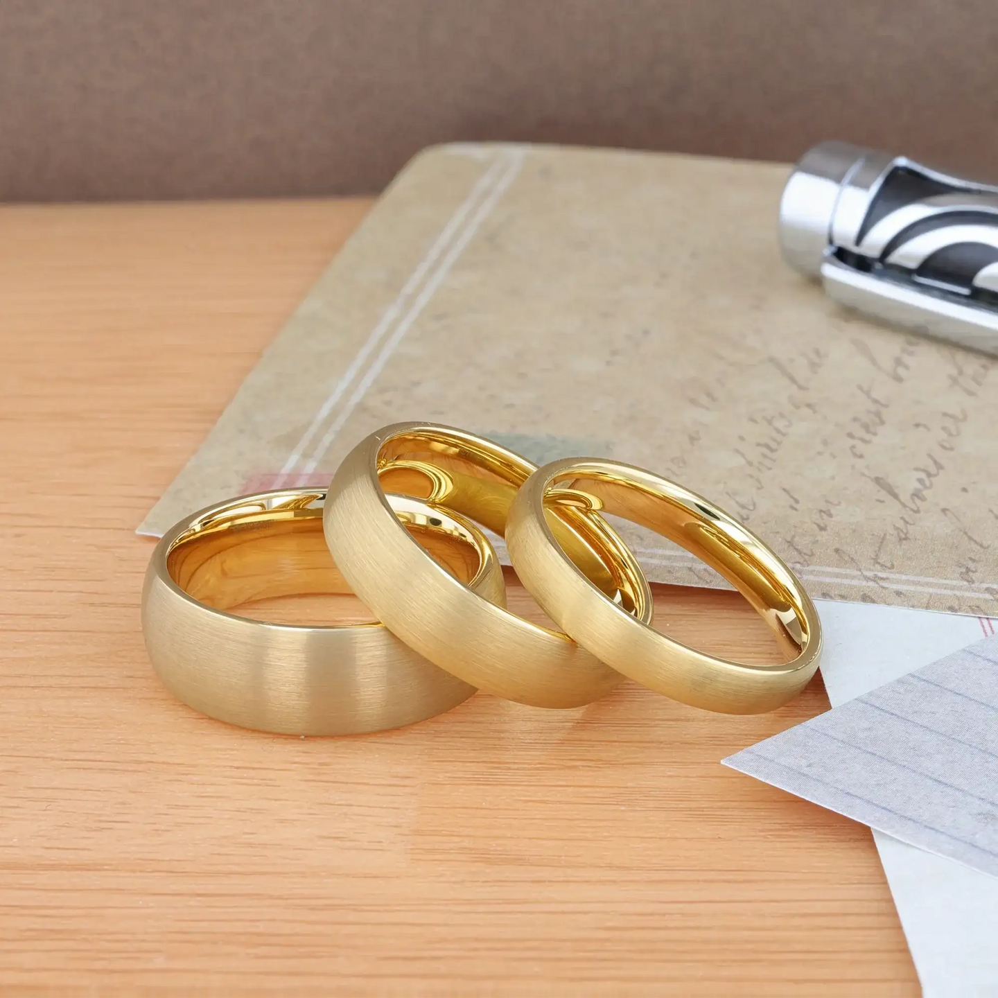 Angled view of a narrower brushed gold-plated tungsten domed ring with polished interior