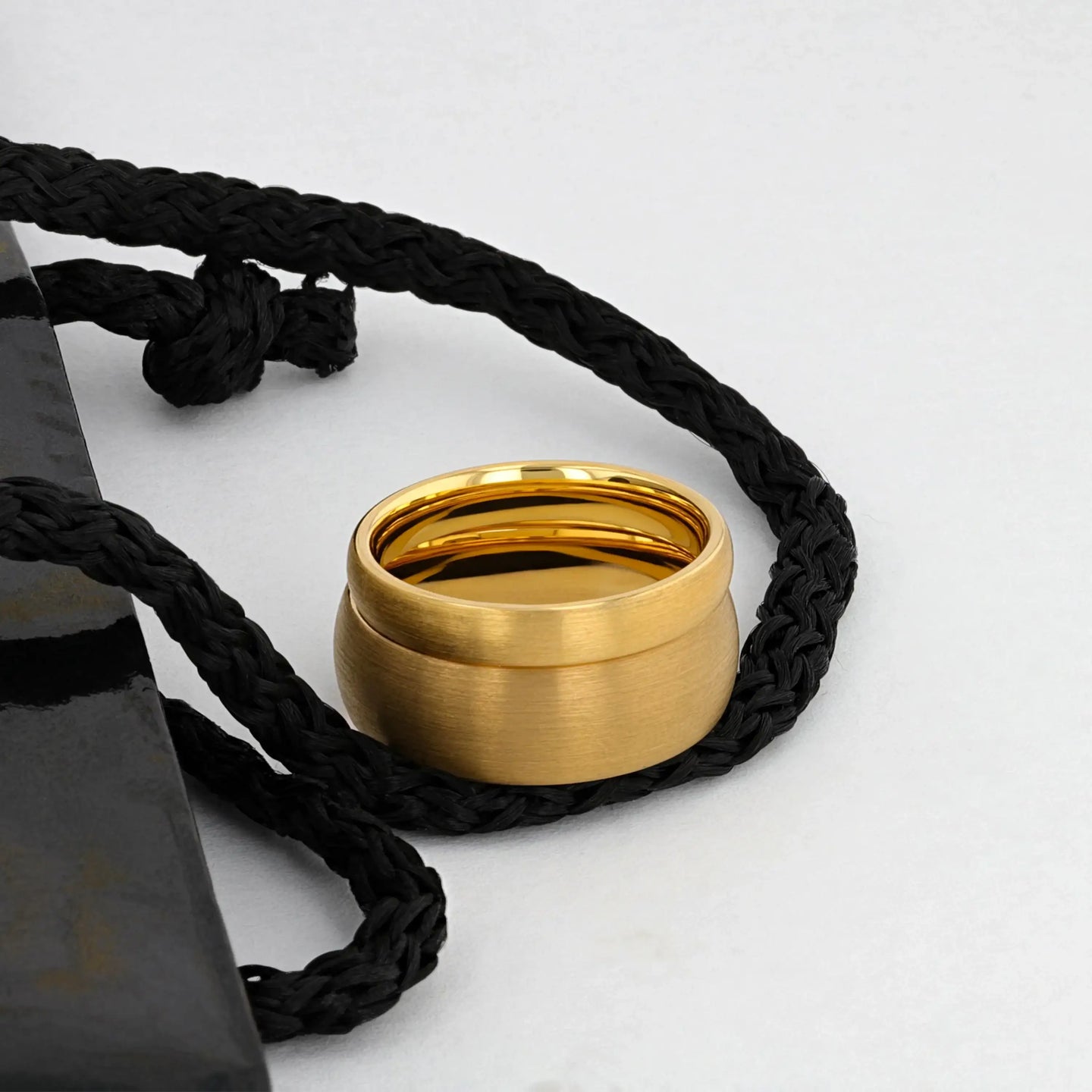 Three brushed gold-plated tungsten rings of varying widths displayed on a white and gold surface