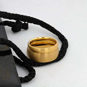 Three brushed gold-plated tungsten rings of varying widths displayed on a white and gold surface