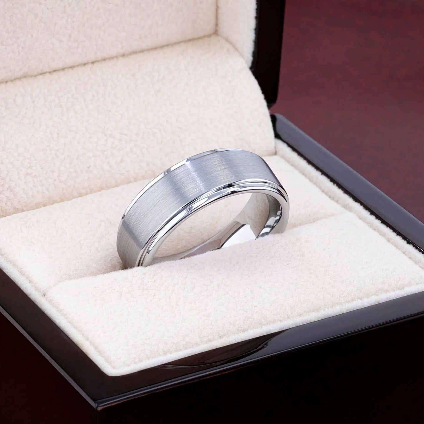 OPTIMUS tungsten ring resting in a cream jewelry box, showing brushed center and polished edges
