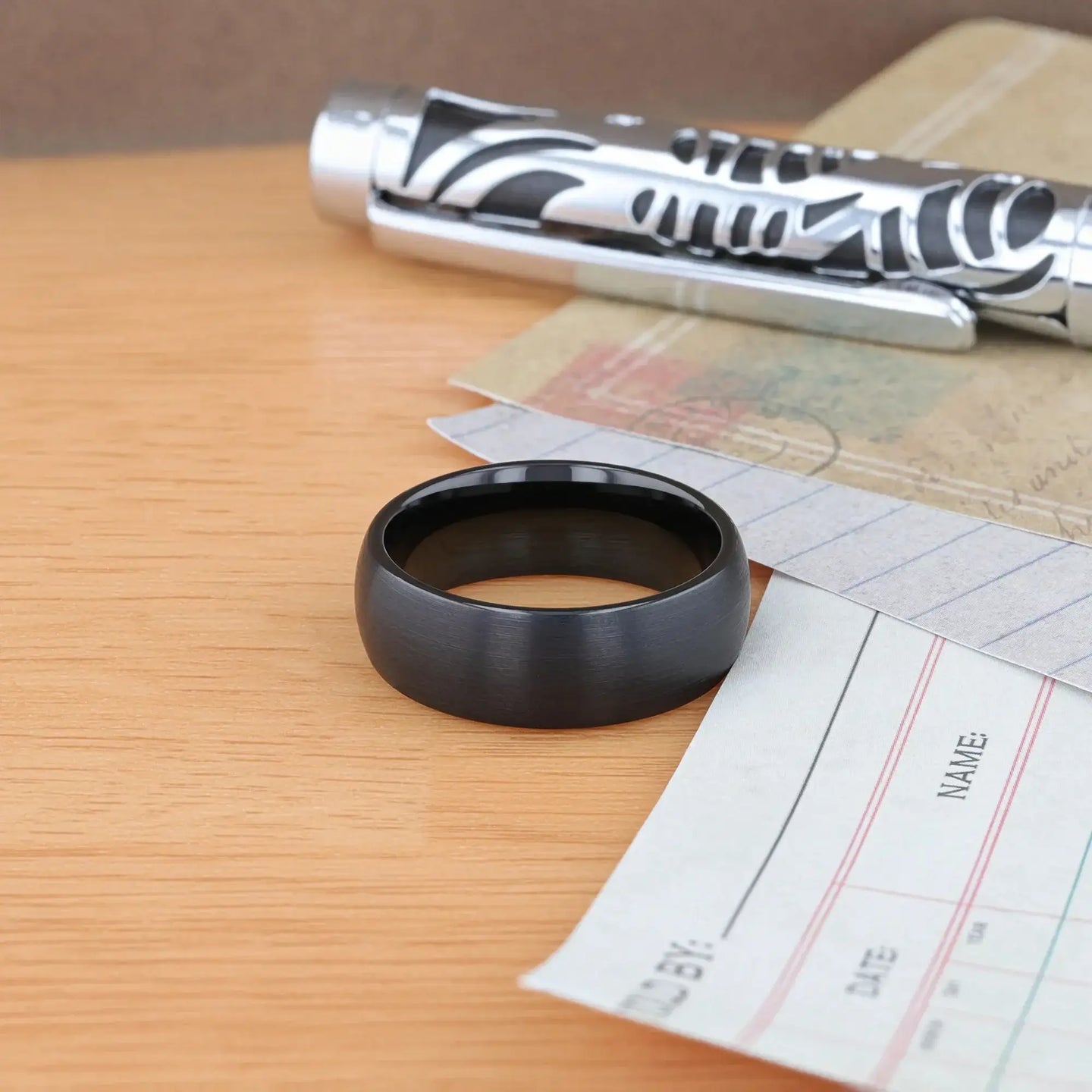 On-hand view of the domed brushed black tungsten ring worn on a person’s finger