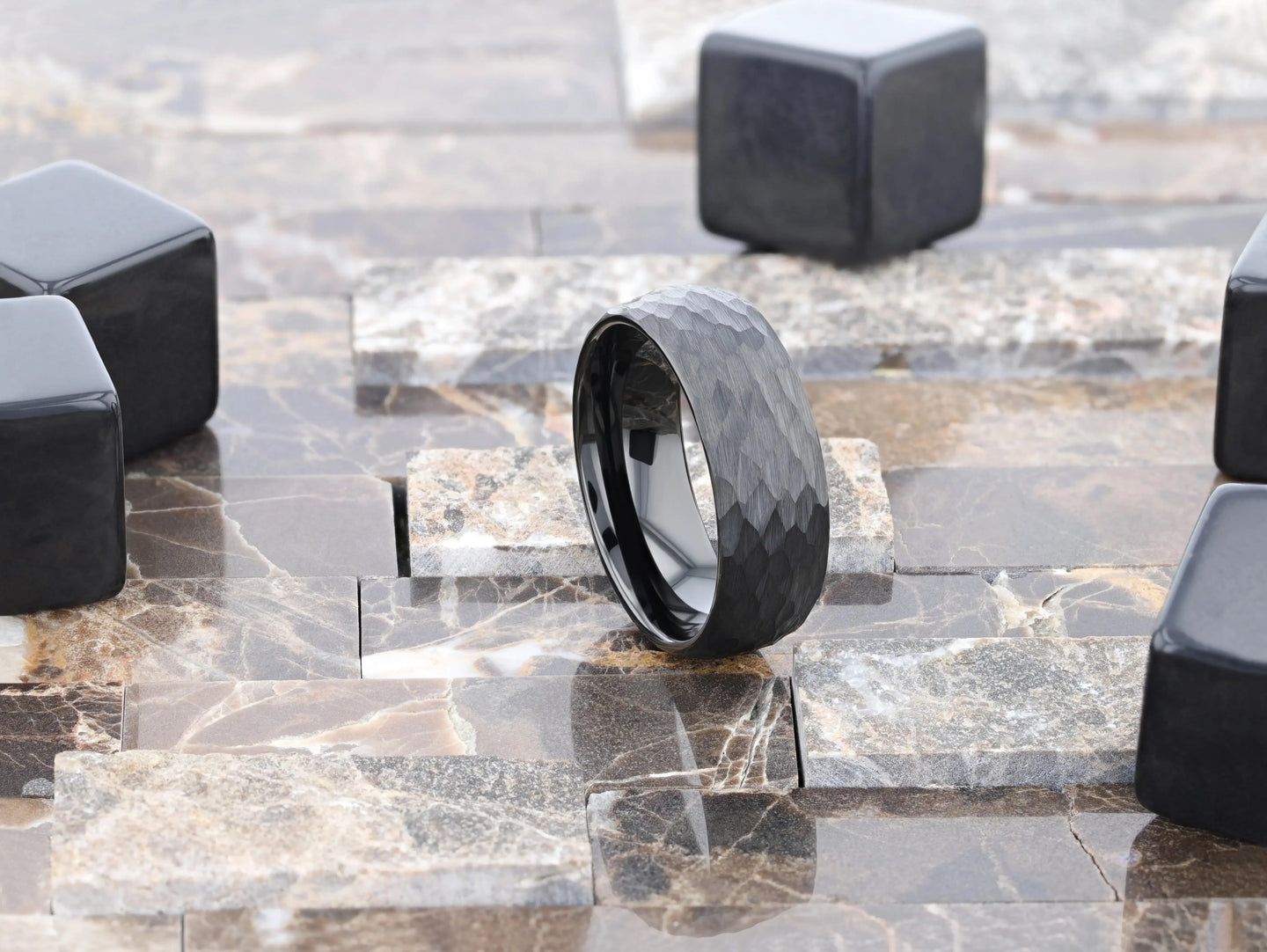 Lifestyle shot of the RENEGADE hammered black tungsten carbide ring standing on a stone surface