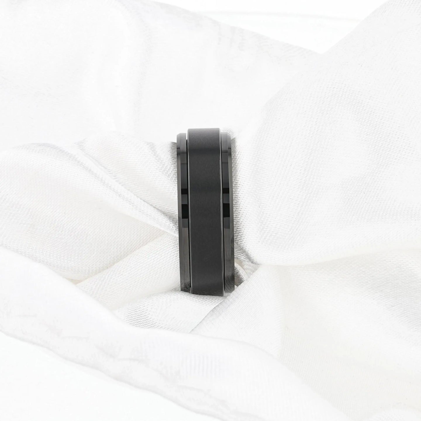 Lifestyle image of the REVOLVE black tungsten spinner ring worn on a hand, showing brushed spinner center