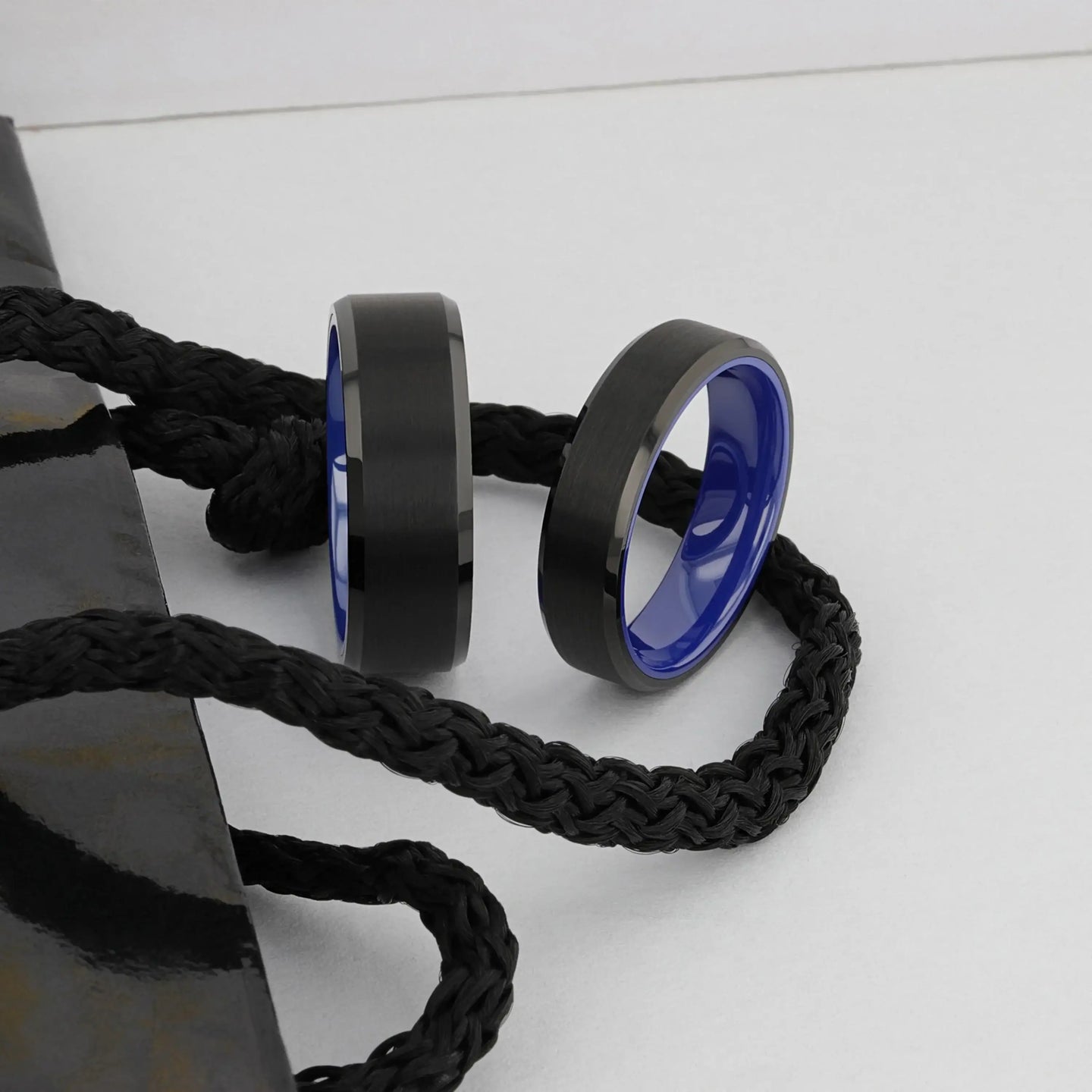 Angled view of the black brushed tungsten ring with polished beveled edges and blue inside.