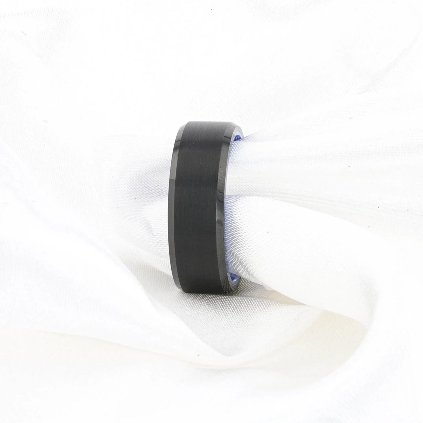 Lifestyle shot of the black brushed tungsten ring with blue inner band on white fabric.