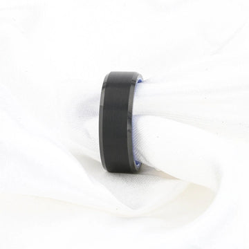 Lifestyle shot of the black brushed tungsten ring with blue inner band on white fabric.
