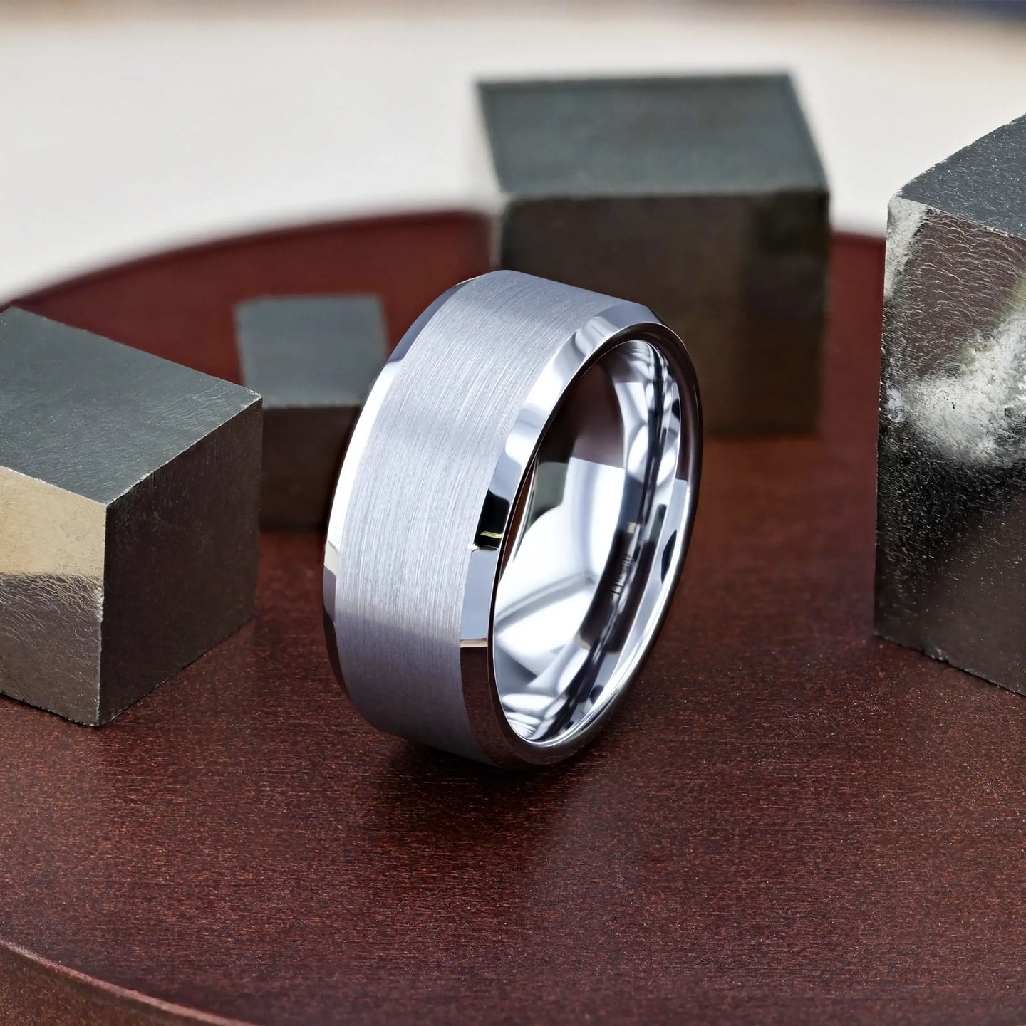 Lifestyle shot of the Sheffield tungsten carbide ring resting among metal cubes, showing brushed center and polished edges