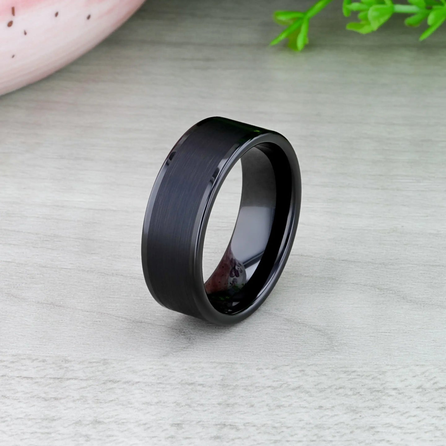 Black tungsten ring displayed in a jewelry box, showing brushed center and glossy sides