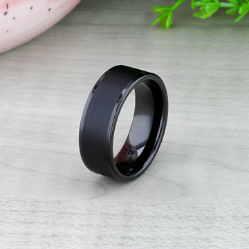 Black tungsten ring displayed in a jewelry box, showing brushed center and glossy sides