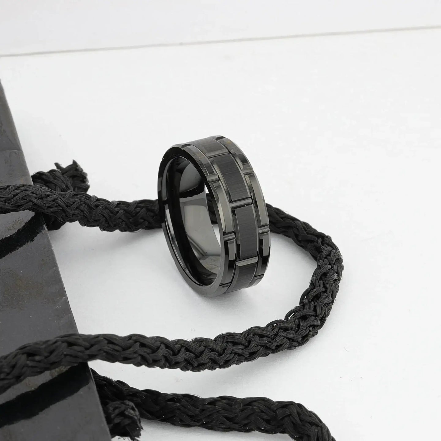 WINDSOR black tungsten carbide ring styled on a surface with braided cord