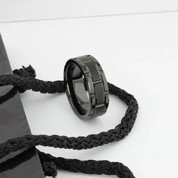 WINDSOR black tungsten carbide ring styled on a surface with braided cord