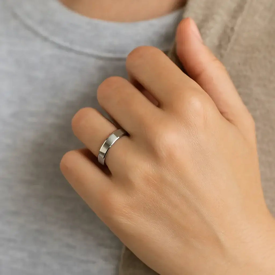 White tungsten beveled-edge wedding band shown worn on a hand
