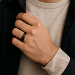 Man wearing a black tungsten carbide ring with a satin center and polished step edges on his ring finger
