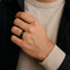 Man wearing a black tungsten carbide ring with a satin center and polished step edges on his ring finger