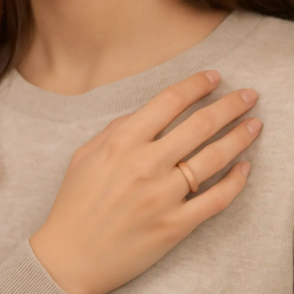 Rose gold sandblasted tungsten carbide ring worn on a woman’s hand to show 4mm width and comfort-fit profile.