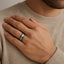 Lifestyle close-up of the ring worn on a hand, showing the black tungsten band with serrated vertical cuts and white gold core