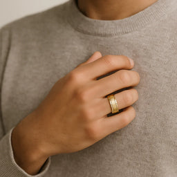 Gold-toned brushed-center band with polished edges worn on a person’s hand, showcasing fit and profile