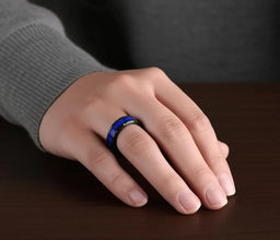 Black tungsten and blue ceramic T-link ring shown worn on hand against dark tabletop