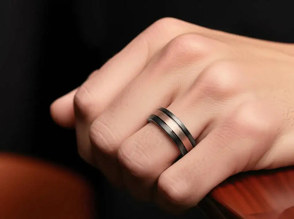 Black and brown tungsten carbide ring worn on a hand, showing brushed brown center band with black edges