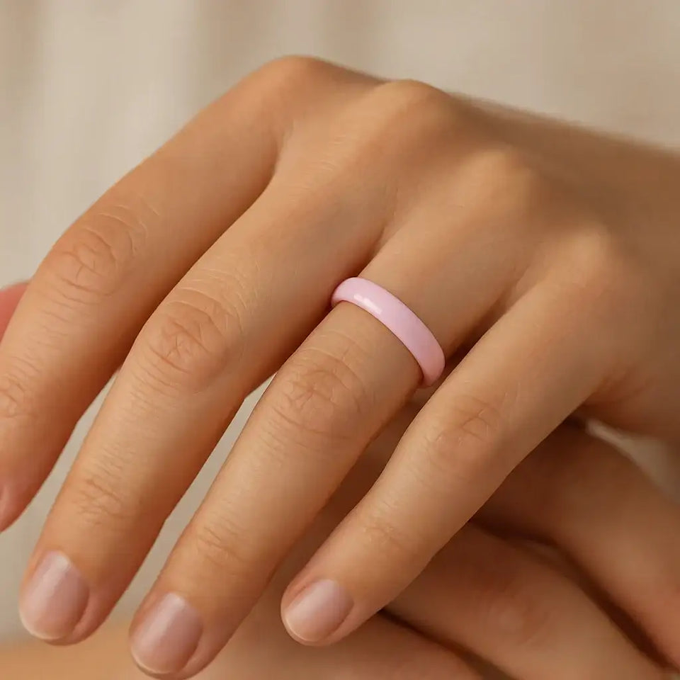 Lifestyle view of the 4mm pink ceramic domed ring worn on a hand, showing its glossy finish.