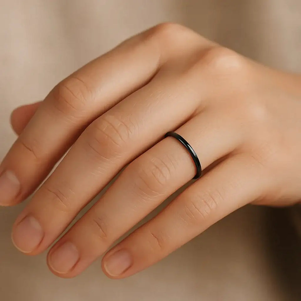 Thin black ceramic ring on a woman's finger, domed profile with polished finish
