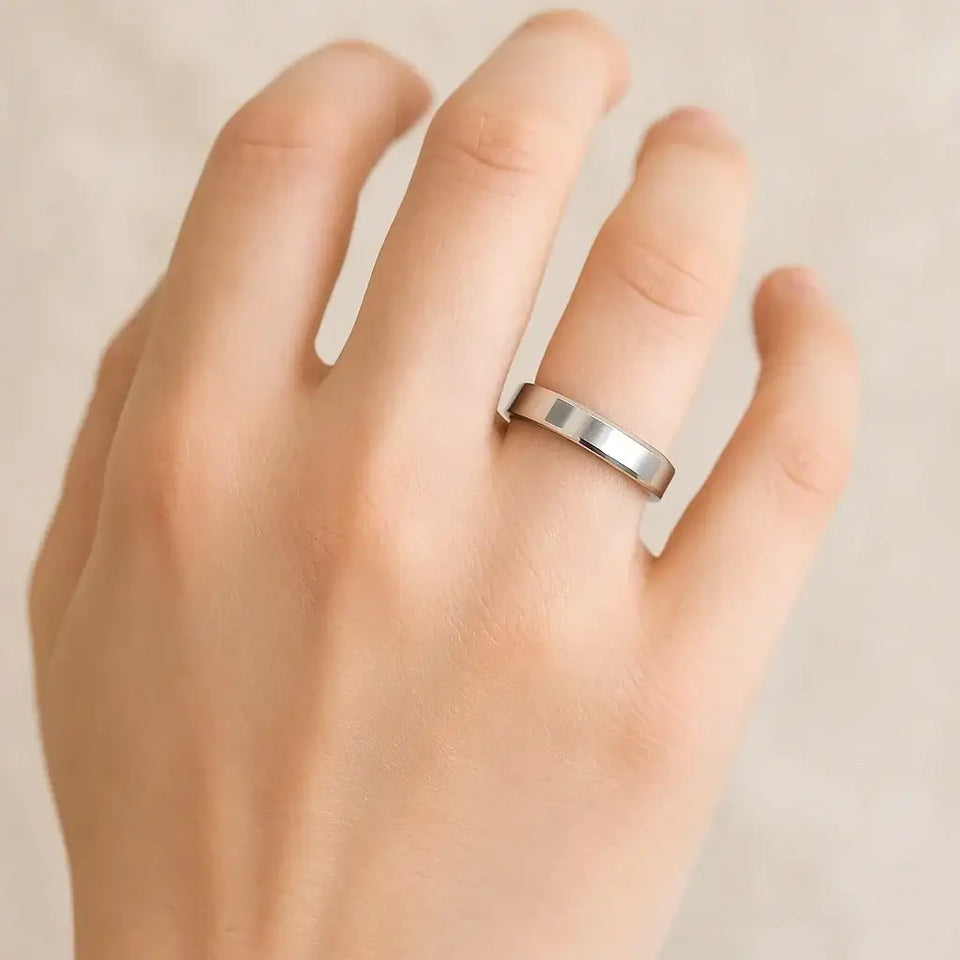 Hand wearing a polished silver flat-center wedding band with beveled edges, 4mm width