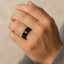 Black titanium beveled wedding ring worn on a person’s hand, showing the 8mm width and glossy finish.