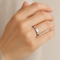 A polished 5mm flat cobalt wedding band worn on a woman's hand, demonstrating the comfort-fit profile