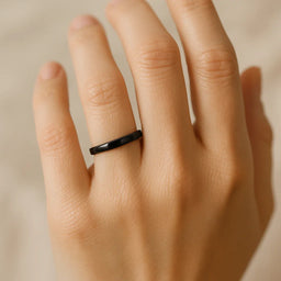 Women's black polished titanium domed ring, 2.5mm, shown on hand for scale