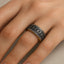 Ring with engraved runes and braided borders worn on a finger, showing the matte black exterior and gold-tone interior