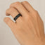 Lifestyle shot of the black knurled titanium ring worn on a hand, showing the flat profile and matte texture